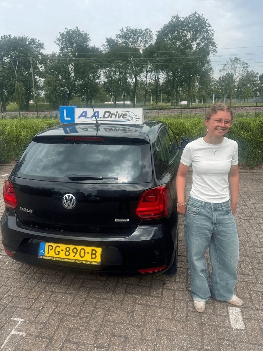 Evi met haar rijbewijs naast de lesauto
